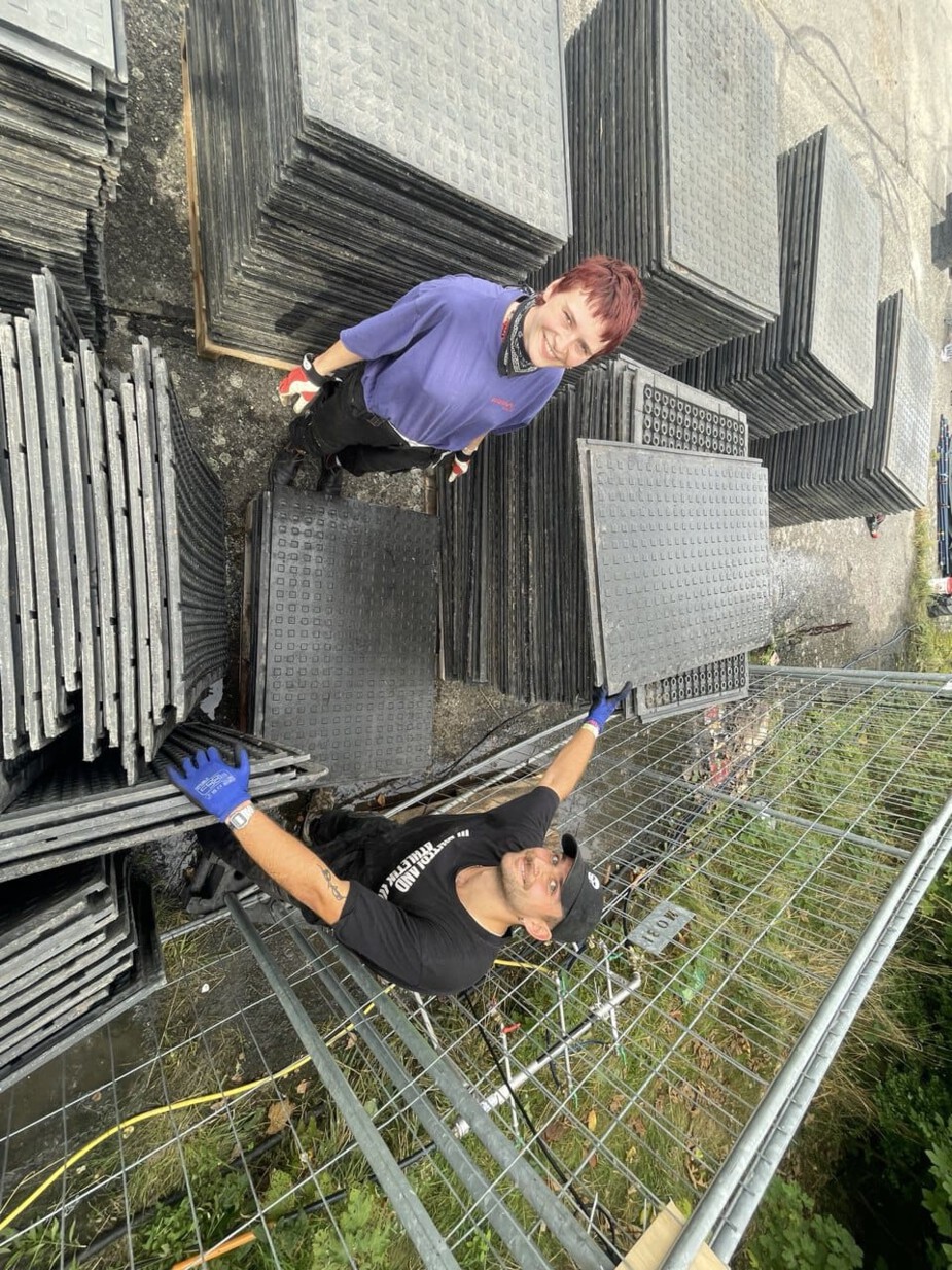 Two people are stacking a pallet of heavy-duty mats. There are around 1,000 mats in total.